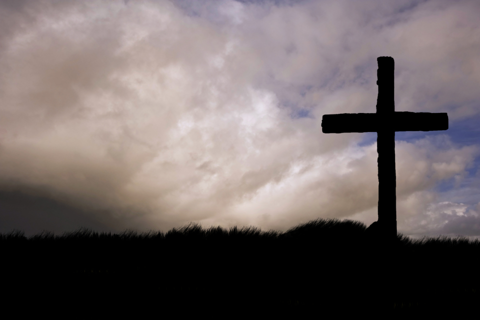 the cross of Christ silhouetted against a stormy sky
