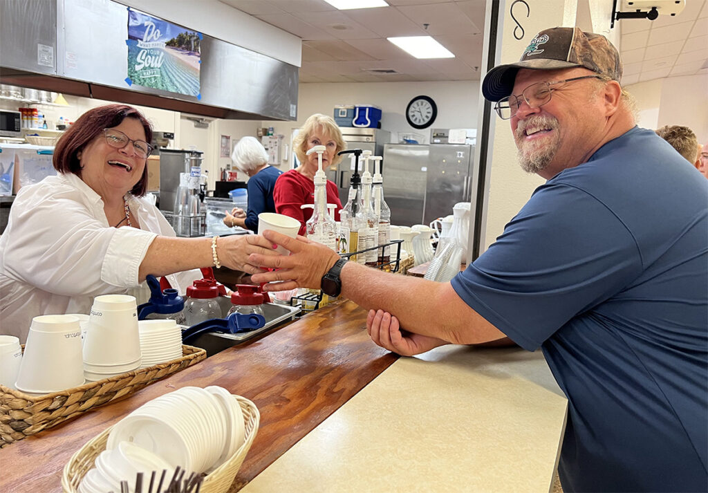 man accepting coffee cup from a woman at the coffee bar